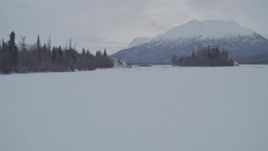 4K aerial stock footage flying low over snow covered, frozen ground and icy river, Knik River Valley, Alaska Aerial Stock Footage | AK0001_1590