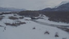 4K aerial stock footage flying over river, snow covered path through woods, Knik River Valley, Alaska Aerial Stock Footage | AK0001_1592