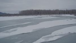 4K aerial stock footage following an icy river toward snow covered shore, Knik River Valley, Alaska Aerial Stock Footage | AK0001_1601