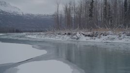 4K aerial stock footage following an icy river between snowy shore, Knik River Valley, Alaska Aerial Stock Footage | AK0001_1602