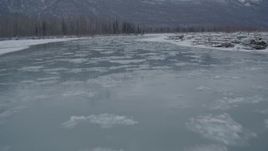 4K aerial stock footage flying low over icy river toward snow covered shore, Knik River Valley, Alaska Aerial Stock Footage | AK0001_1603