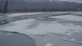 4K aerial stock footage flying low over icy river toward snow covered shore, Knik River Valley, Alaska Aerial Stock Footage | AK0001_1605