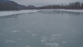 4K aerial stock footage flying low over icy river toward snow covered shore, Knik River Valley, Alaska Aerial Stock Footage | AK0001_1607