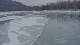 4K aerial stock footage flying low over icy river toward snow covered shore, Knik River Valley, Alaska Aerial Stock Footage | AK0001_1608