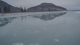 4K aerial stock footage icy river, snowy shore, reveal Glenn Highway bridge, Knik River Valley, Alaska Aerial Stock Footage | AK0001_1611
