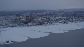 4K aerial stock footage flying away from snowy Downtown Anchorage over Cook Inlet at twilight, Alaska Aerial Stock Footage | AK0001_1655