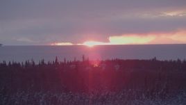4K aerial stock footage the sun setting behind clouds, Point MacKenzie, Alaska in snow Aerial Stock Footage | AK0001_1675