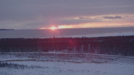 4K aerial stock footage the sunset behind clouds seen from snow covered Point MacKenzie, Alaska Aerial Stock Footage | AK0001_1676