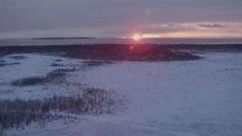 4K aerial stock footage the setting sun behind clouds seen from snow covered Point MacKenzie, Alaska Aerial Stock Footage | AK0001_1678