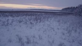 4K aerial stock footage flying low over frozen, snow covered ground at twilight, Point MacKenzie, Alaska Aerial Stock Footage | AK0001_1697