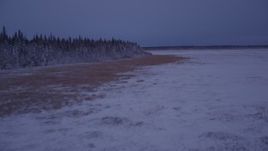 4K aerial stock footage flying over snow covered ground along edge of forest, twilight, Point MacKenzie, Alaska Aerial Stock Footage | AK0001_1708