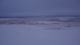 4K aerial stock footage flying low over frozen, snow covered ground at twilight, Point MacKenzie, Alaska Aerial Stock Footage | AK0001_1710