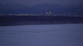 4K aerial stock footage tilt up from snowy ground revealing Downtown Anchorage skyline, Alaska, night Aerial Stock Footage | AK0001_1714