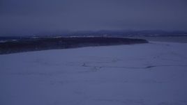 4K aerial stock footage flying over snow covered ground toward forest at night, Point MacKenzie, Alaska Aerial Stock Footage | AK0001_1715