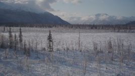 4K aerial stock footage flying low over frozen, snowy ground toward Chugach Mountains, Alaska Aerial Stock Footage | AK0001_1773