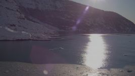 4K aerial stock footage the sun reflecting off water in Harriman Fjord near snow covered glacier, Alaska Aerial Stock Footage | AK0001_1820