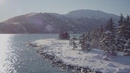 4K aerial stock footage flying low over surface of Harriman Fjord, then over snowy, wooded shore, Alaska Aerial Stock Footage | AK0001_1831