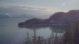 4K aerial stock footage flying toward the snowy, wooded shore of a bay, Port Wells, Alaska Aerial Stock Footage | AK0001_1849