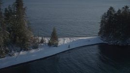 4K aerial stock footage descend to snow covered peninsula, pan to forest, Port Wells, Alaska Aerial Stock Footage | AK0001_1861
