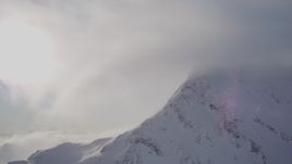 4K aerial stock footage flying by cloud, snow covered mountains summit, Chugach Mountains, Alaska Aerial Stock Footage | AK0001_1915