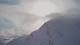 4K aerial stock footage flying by a snowy mountain capped by sunlit clouds, Chugach Mountains, Alaska Aerial Stock Footage | AK0001_1916