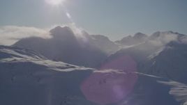 4K aerial stock footage low clouds over snowy summits with sun overhead, Chugach Mountains, Alaska Aerial Stock Footage | AK0001_1918