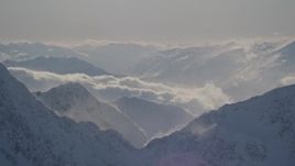 4K aerial stock footage snowy, windblown mountain ranges and low clouds in Kenai Mountains, Alaska Aerial Stock Footage | AK0001_1977
