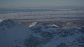 4K aerial stock footage cloud covered Anchorage, seen from snowy Chugach Mountains, Alaska Aerial Stock Footage | AK0001_1996