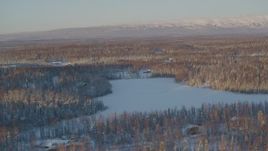 4K aerial stock footage houses near frozen lake, snowy forest in Knik-Fairview, Alaska, sunset Aerial Stock Footage | AK0001_2068