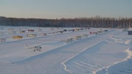 4K aerial stock footage flying by parked aircraft at snow covered Shawn Field at sunset, Wasilla, Alaska Aerial Stock Footage | AK0001_2074