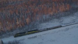 4K aerial stock footage tracking a train running by snowy trees at sunset, Wasilla, Alaska Aerial Stock Footage | AK0001_2079