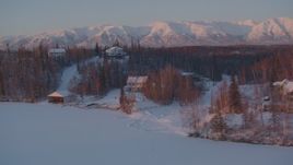 4K aerial stock footage fly by snow covered homes on frozen Cottonwood Lake, Wasilla, Alaska, twilight Aerial Stock Footage | AK0001_2090