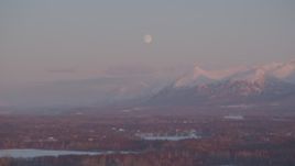 4K aerial stock footage the moon over the snow covered Chugach Mountains at twilight, Wasilla, Alaska Aerial Stock Footage | AK0001_2092