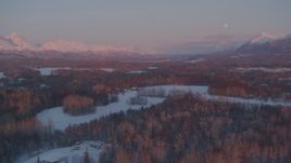4K aerial stock footage fly over snowy rural homes, reveal moon over mountains, Palmer, Alaska, twilight Aerial Stock Footage | AK0001_2095