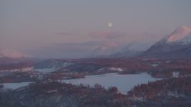 4K aerial stock footage the moon over the snow covered Chugach Mountains at twilight, Palmer, Alaska Aerial Stock Footage | AK0001_2098