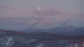 4K aerial stock footage the moon over the snow covered Chugach Mountains at sunset, Alaska Aerial Stock Footage | AK0001_2101