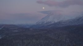 4K aerial stock footage the moon over the snow covered Chugach Mountains at twilight, Alaska Aerial Stock Footage | AK0001_2107