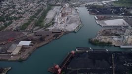 4.8K aerial stock footage tilt from piles of petroleum coke by the Calumet River to reveal more industrial buildings, East Side Chicago, Illinois Aerial Stock Footage | AX0001_167