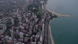 4.8K aerial stock footage follow Lake Shore Drive by apartment buildings, and tilt to Lincoln Park at sunset, North Chicago, Illinois Aerial Stock Footage | AX0003_053
