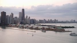 4.8K aerial stock footage orbit Navy Pier, revealing Downtown Chicago skyline, on a cloudy day at sunset, Illinois Aerial Stock Footage | AX0003_064