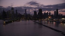 4.8K aerial stock footage of flying over Lake Michigan to approach Downtown Chicago skyline at twilight, Illinois Aerial Stock Footage | AX0003_129