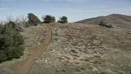 5K aerial stock footage fly low over dirt roads and a mountain ridge in the Mojave Desert, California Aerial Stock Footage | AX0005_055E
