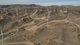 5K aerial stock footage of approaching a field full of windmills at a desert wind farm in Antelope Valley, California Aerial Stock Footage | AX0006_020E