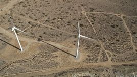 5K aerial stock footage tilt to a bird's eye view of a pair of windmills in the Mojave Desert, California Aerial Stock Footage | AX0006_040