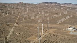 5K aerial stock footage of a wide orbit around rows of windmills at a desert wind energy farm in California Aerial Stock Footage | AX0006_042