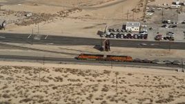 5K aerial  video approach a train running by the town of Mojave in California Aerial Stock Footage | AX0006_053