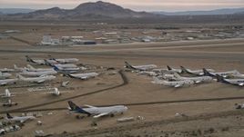 5K aerial stock footage orbit several aircraft at a boneyard by a small airport in the desert, Mojave Air and Space Port, California Aerial Stock Footage | AX0006_085
