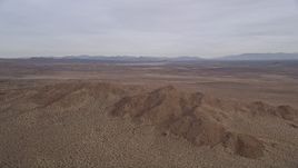 5K aerial stock footage of panning across open desert to reveal and approach mountains, Mojave Desert, California Aerial Stock Footage | AX0006_115