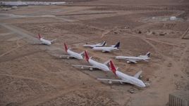 5K aerial stock footage orbit seven airliners parked at aircraft boneyard in Sunset, Victorville Airport, California Aerial Stock Footage | AX0007_013