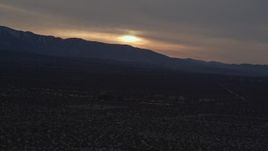 5K aerial stock footage of sun-lit clouds over distant mountains seen from the Mojave Desert at twilight, California Aerial Stock Footage | AX0007_031